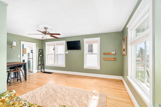 interior space featuring a wealth of natural light, baseboards, wood finished floors, and ceiling fan