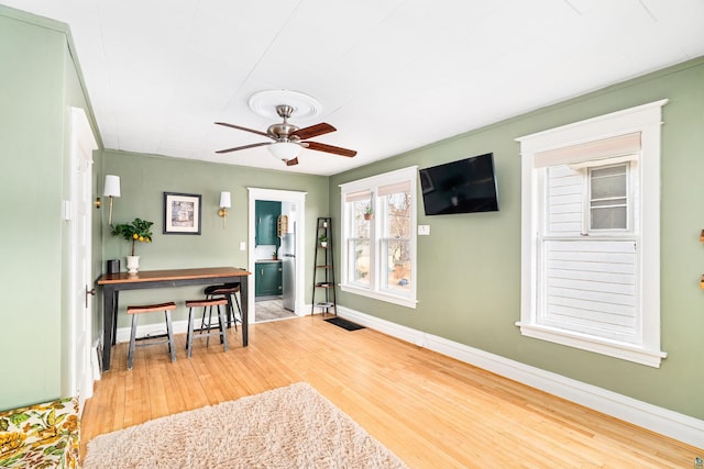 interior space featuring ceiling fan, baseboards, and wood finished floors