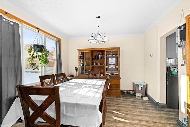 dining space featuring an inviting chandelier, wood finished floors, and baseboards