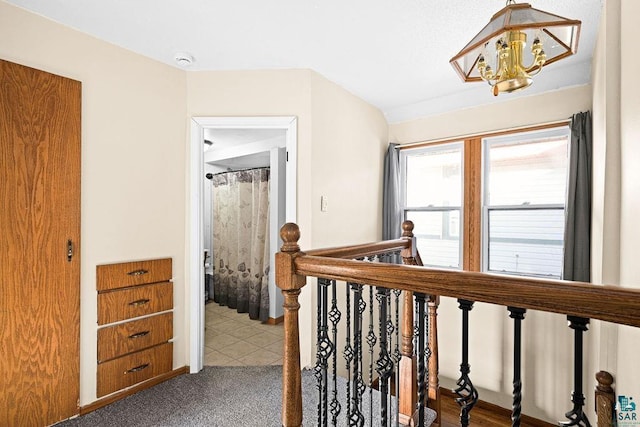 corridor with an upstairs landing and a chandelier