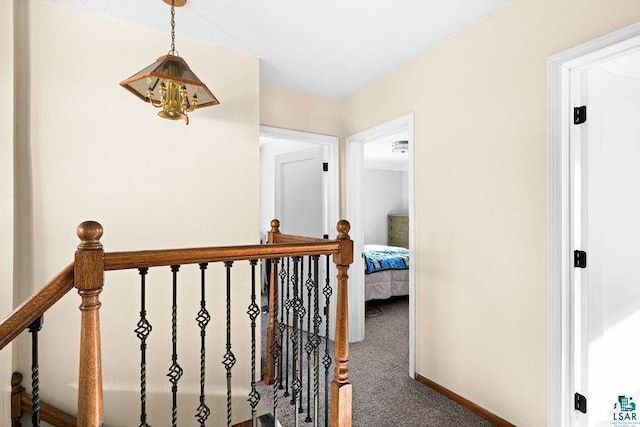 hall with an upstairs landing, baseboards, and carpet