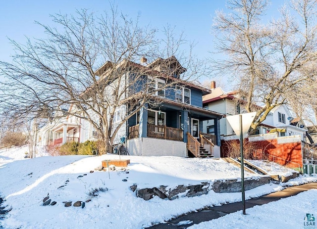 american foursquare style home featuring a porch and a chimney