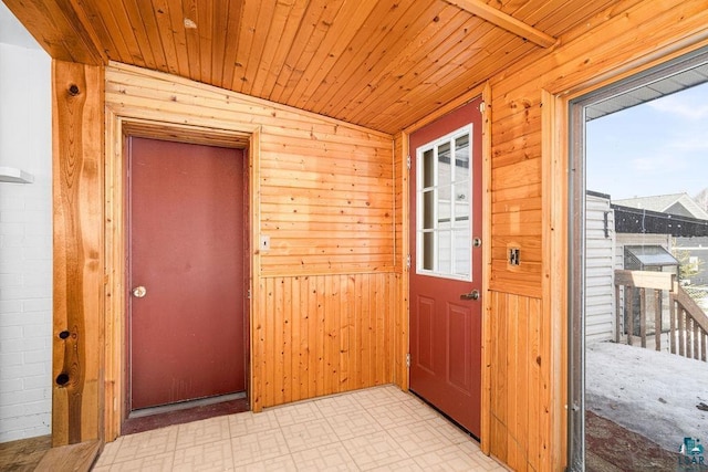 foyer entrance featuring light floors, wood walls, and wooden ceiling