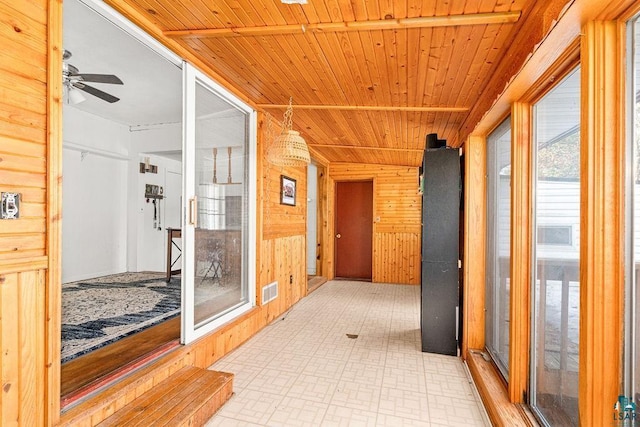 hallway featuring tile patterned floors, visible vents, wooden walls, and wooden ceiling