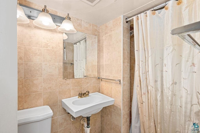 bathroom with visible vents, a sink, curtained shower, tile walls, and toilet