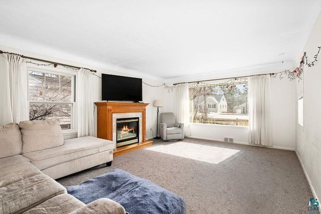 carpeted living room with a wealth of natural light, visible vents, baseboards, and a premium fireplace