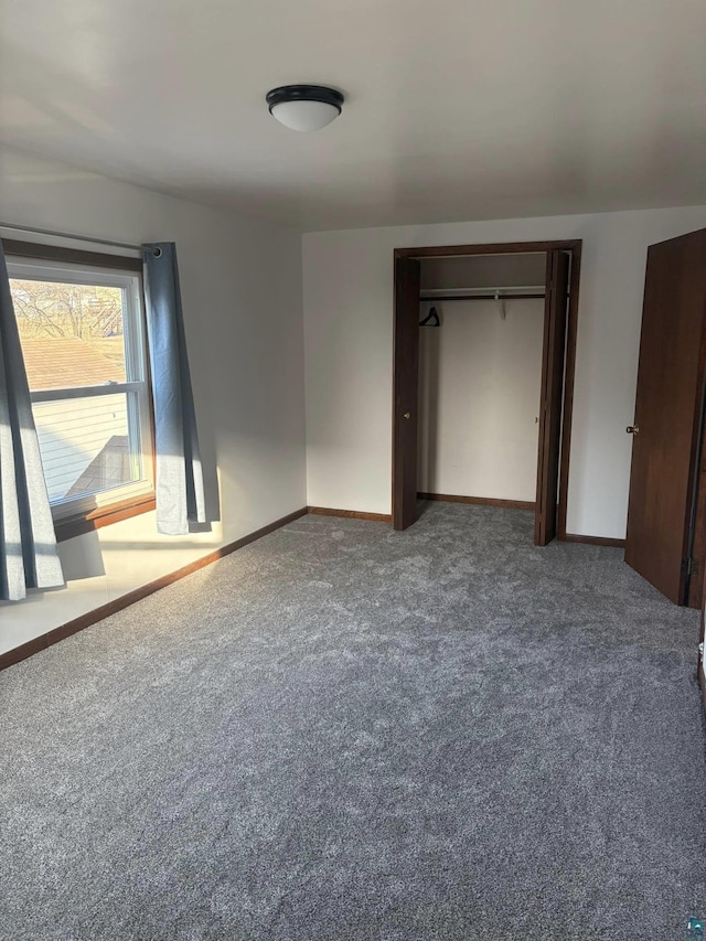 unfurnished bedroom with a closet, carpet flooring, and baseboards