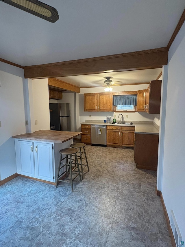 kitchen with a sink, stainless steel appliances, a peninsula, brown cabinetry, and baseboards