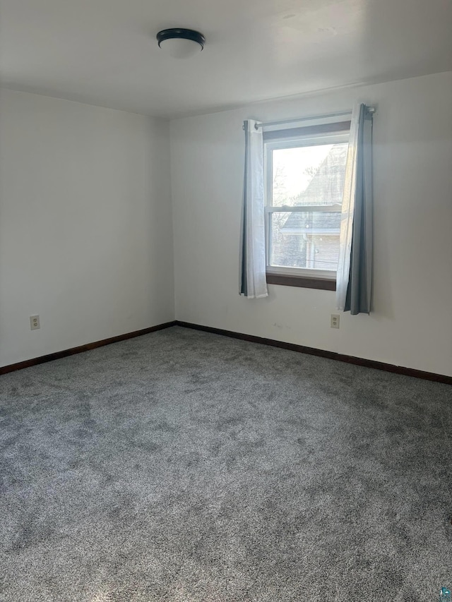 carpeted spare room featuring baseboards