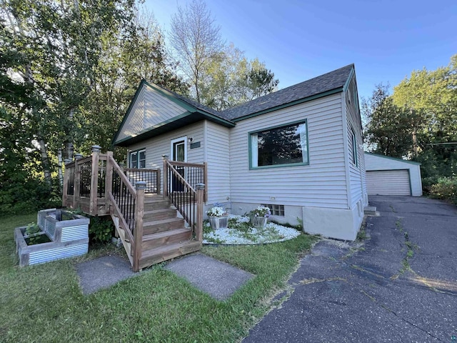 bungalow-style house featuring an outbuilding, roof with shingles, a wooden deck, a garden, and a garage