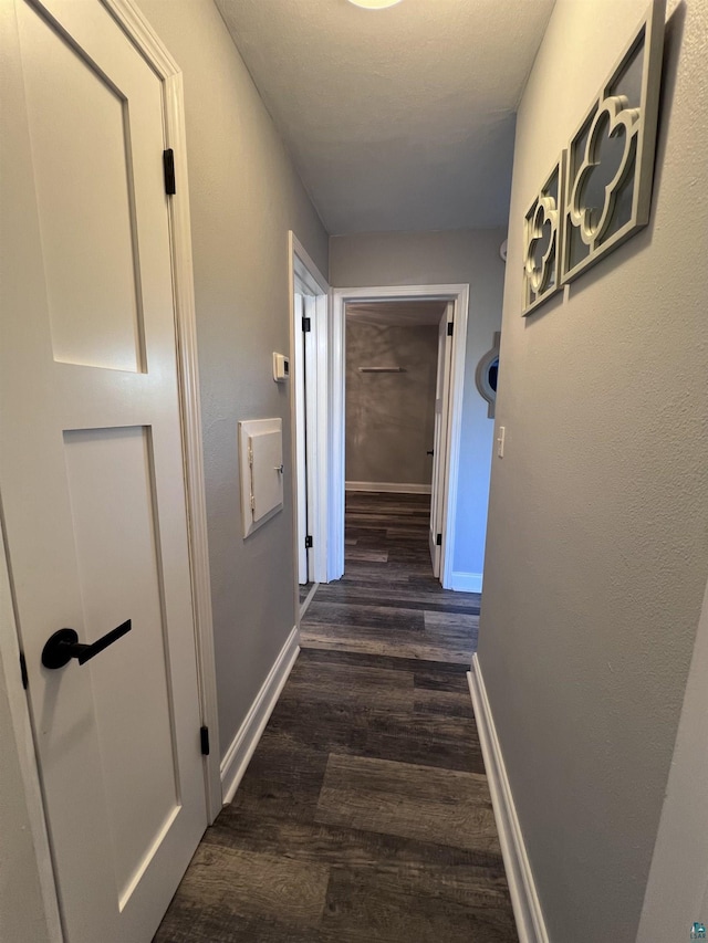 hallway with baseboards and dark wood-type flooring