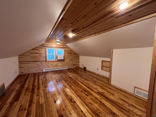 additional living space featuring visible vents, wooden walls, a baseboard radiator, vaulted ceiling, and wood-type flooring