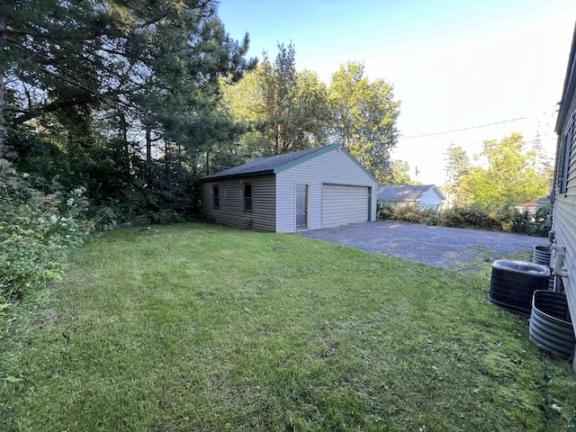 view of yard with an outbuilding, central AC unit, aphalt driveway, and a garage