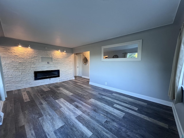 unfurnished living room featuring a stone fireplace, baseboards, and wood finished floors