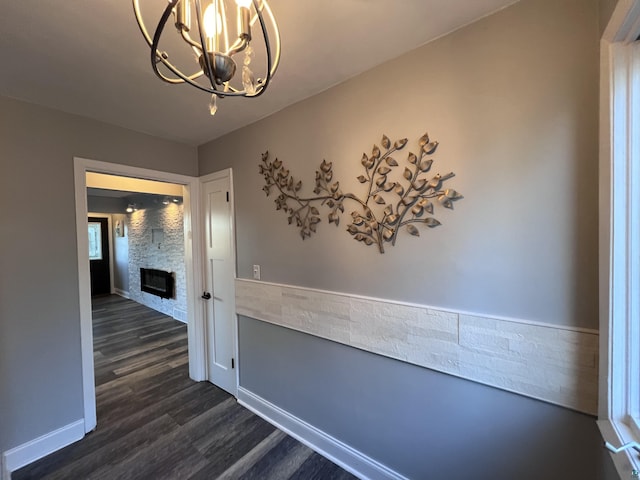 hallway with dark wood-type flooring and a chandelier