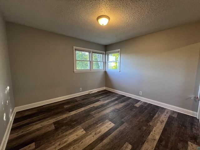 empty room featuring baseboards, dark wood-type flooring, and a textured ceiling