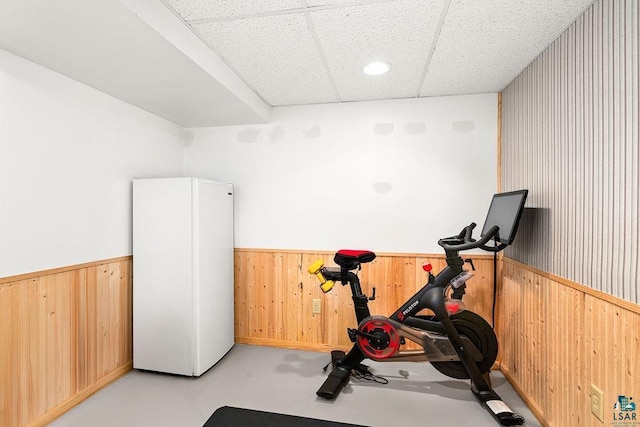 exercise area with a wainscoted wall, a paneled ceiling, and wooden walls