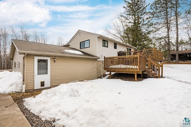 snow covered house with a wooden deck