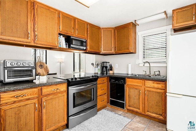 kitchen with brown cabinetry, a toaster, a sink, appliances with stainless steel finishes, and dark countertops