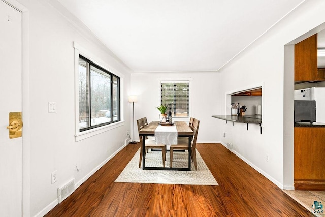 dining space featuring visible vents, baseboards, and wood finished floors