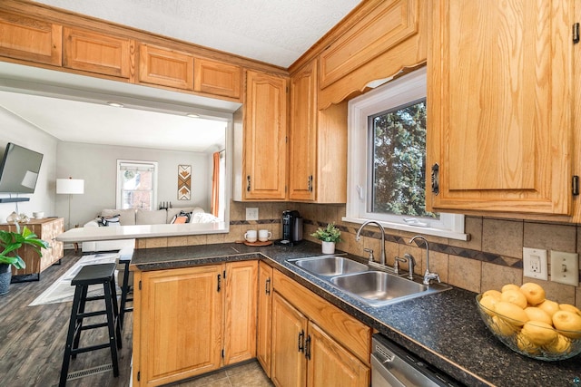 kitchen featuring a sink, dark countertops, backsplash, and dishwasher