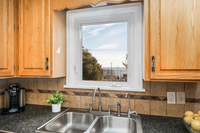 kitchen with tasteful backsplash, dark stone countertops, and a sink