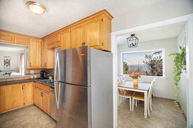 kitchen featuring a notable chandelier, dark countertops, a textured ceiling, appliances with stainless steel finishes, and baseboards