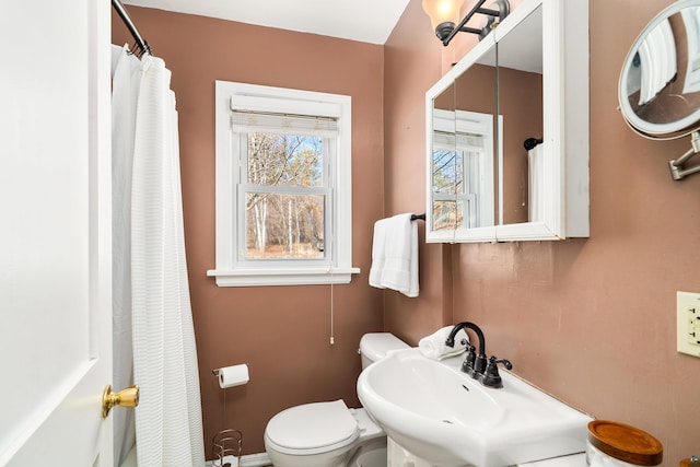 full bath featuring toilet, a shower with shower curtain, and a sink