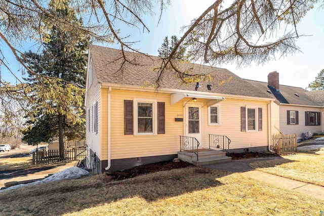 view of front of home featuring a shingled roof, a front yard, fence, and a chimney