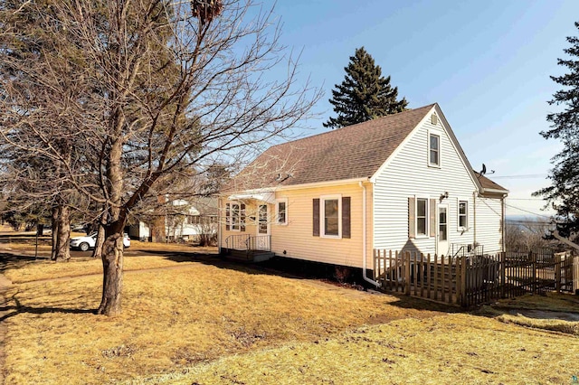 view of home's exterior featuring a yard, fence, and roof with shingles