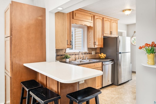 kitchen with backsplash, appliances with stainless steel finishes, a breakfast bar, and a sink