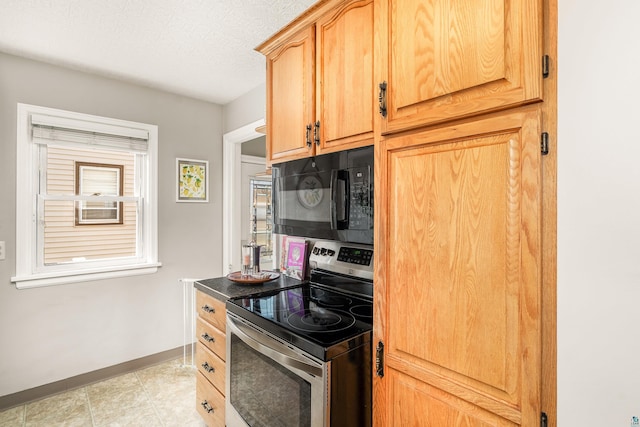 kitchen featuring baseboards, black microwave, light brown cabinetry, stainless steel electric range oven, and a textured ceiling