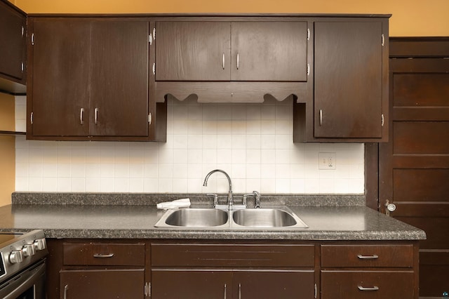 kitchen featuring a sink, tasteful backsplash, dark countertops, dark brown cabinetry, and gas range