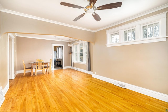 spare room featuring a ceiling fan, baseboards, visible vents, crown molding, and light wood-type flooring