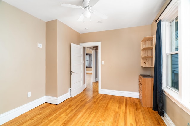 empty room featuring a ceiling fan, baseboards, and light wood-type flooring