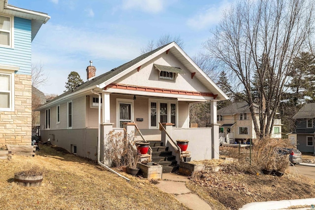 bungalow-style home with covered porch and a chimney