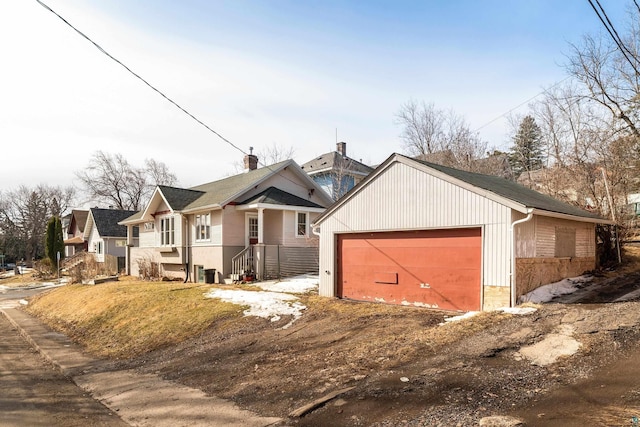 view of front of house with a detached garage, central AC unit, and an outdoor structure