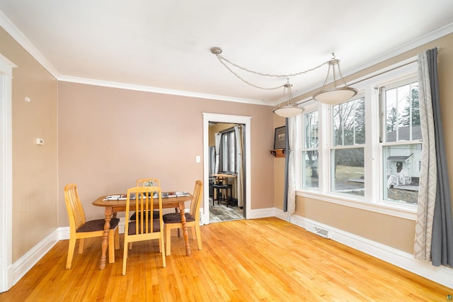 dining room with visible vents, baseboards, light wood finished floors, and ornamental molding