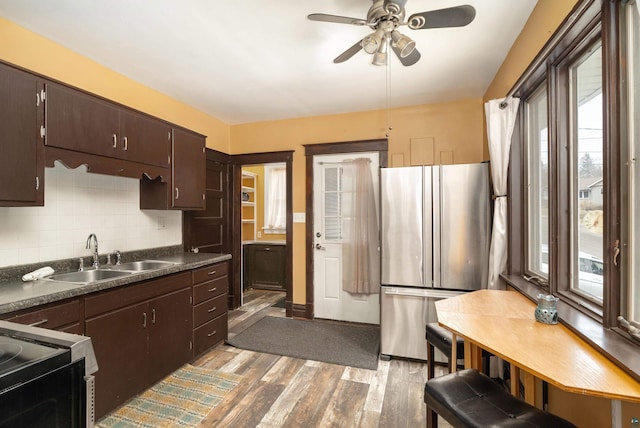 kitchen featuring a ceiling fan, a sink, tasteful backsplash, freestanding refrigerator, and light wood finished floors