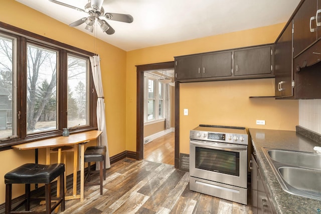 kitchen featuring stainless steel electric range oven, plenty of natural light, wood finished floors, and a sink