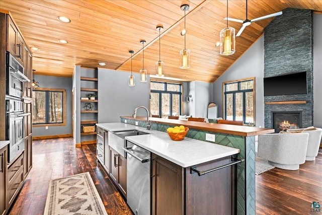 kitchen with dark wood-type flooring, a center island with sink, a sink, stainless steel dishwasher, and open floor plan