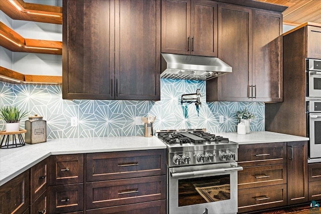 kitchen featuring dark brown cabinets, backsplash, under cabinet range hood, and stainless steel appliances