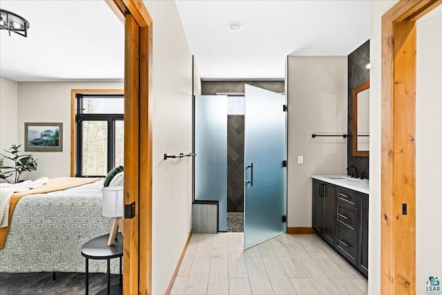 ensuite bathroom featuring vanity, wood finished floors, baseboards, a stall shower, and connected bathroom