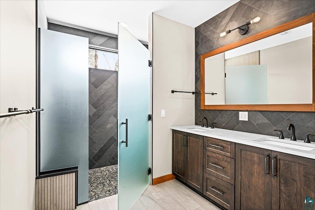 full bath featuring decorative backsplash, a shower stall, double vanity, and a sink