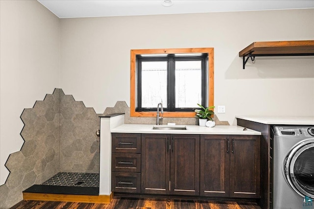 clothes washing area featuring dark wood finished floors, washer / dryer, cabinet space, and a sink