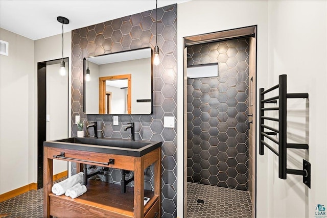 bathroom with a tile shower, visible vents, and baseboards