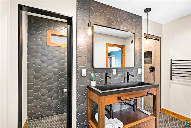 bathroom with tasteful backsplash, a tile shower, radiator, baseboards, and vanity