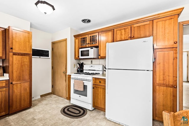 kitchen featuring visible vents, brown cabinets, white appliances, and light countertops