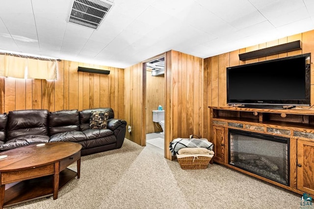 carpeted living area featuring a fireplace, visible vents, and wood walls