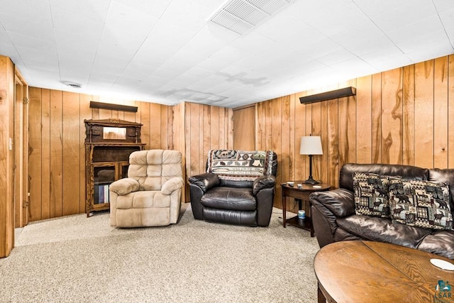 living room featuring visible vents, wooden walls, and carpet flooring